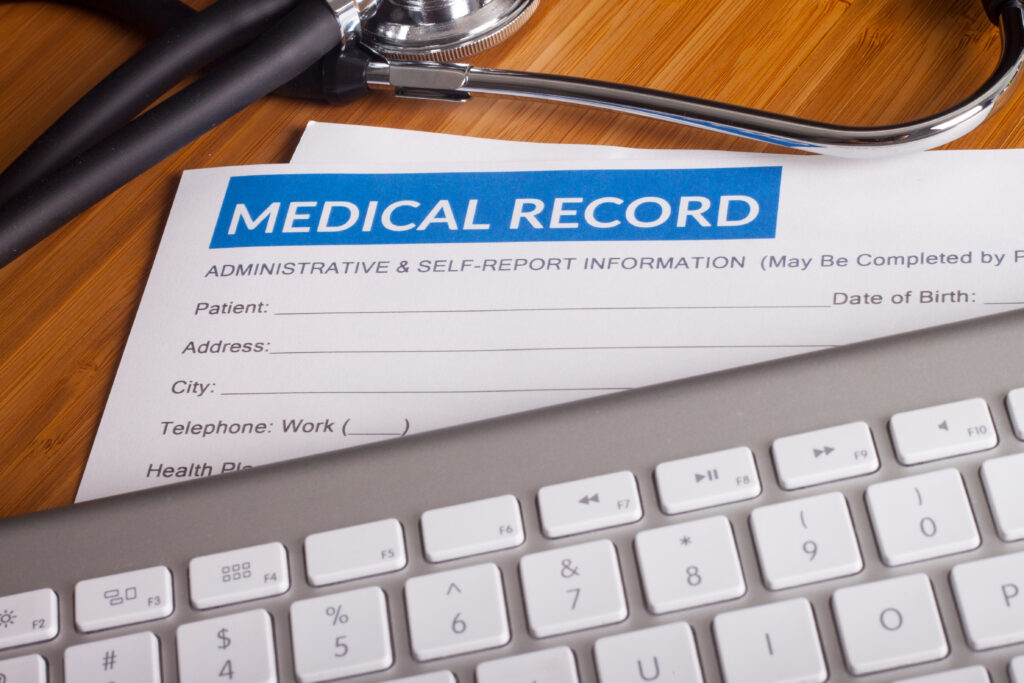 Close-up of a blank medical record form, a stethoscope, and a computer keyboard, representing healthcare documentation and the management of patient information.