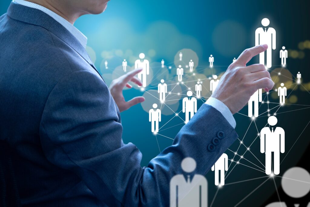 Business professional interacting with a digital network of human figures representing workforce management, illustrating the concept of optimizing human resources and team management through technology and strategic planning.